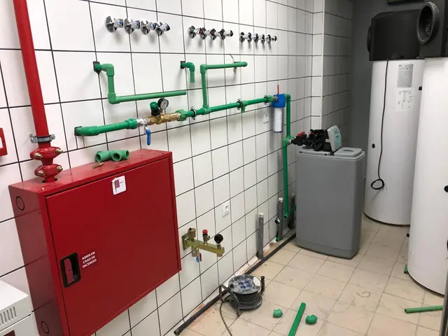 Entrada de agua con reductora de presión, filtro, descalcificador y acumuladores en la sala técnica de un local