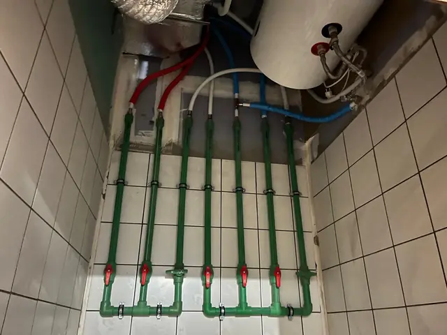 Colectores de polipropileno con una llave por circuito, conectados a las tuberías de agua fría y caliente junto a un termo eléctrico