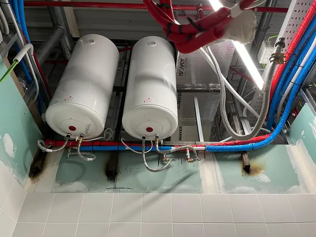 Dos termos eléctricos con conexiones flexibles y tubería aislada de agua fría y caliente en falso techo