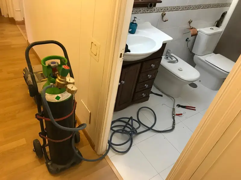 Botella de gas trazador conectada a la instalación de un baño para localizar una fuga oculta sin romper