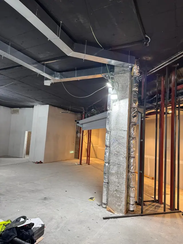 Local diáfano en obra con conductos, bajantes aislados y estructura metálica de la nueva distribución