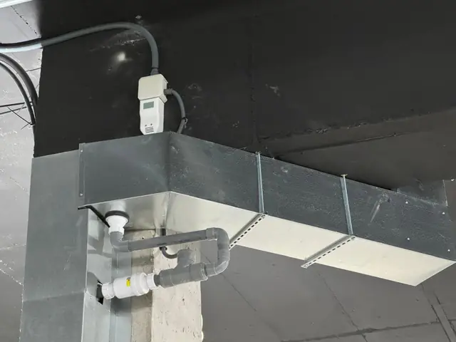 Desagüe de condensados con sifón y válvula antirretorno bajo un conducto de climatización