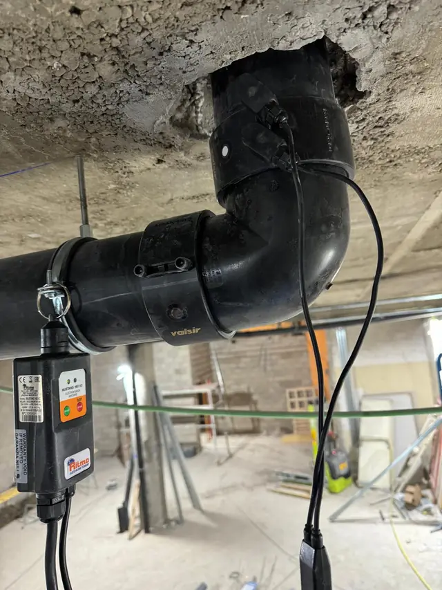 Máquina de electrofusión soldando un codo de polietileno en la red de saneamiento colgada del forjado